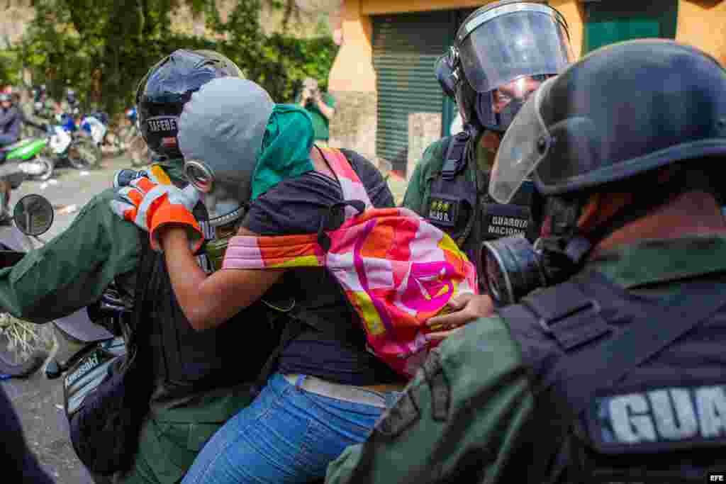 Miembros de la Guardia Nacional Bolivariana detienen a una joven