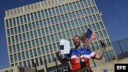 Un hombre posa con sus documentos migratorios frente a la Embajada de los EEUU