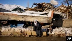 Zehra Kurukafa pasa junto a una casa destruida en la localidad de Polat, Turquía, el domingo 12 de febrero de 2023. (AP Foto/Francisco Seco)